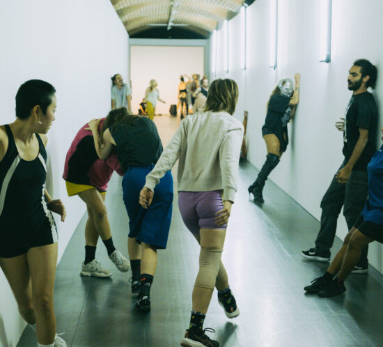 Performers dancing against a white wall